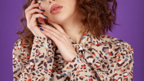 Vertical photo curly-haired girl put her hands together and looking at the camera on purple background. High quality photo